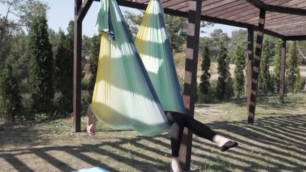 Jonge vrouw beoefent anti-zwaartekracht yoga op hangmat in Park. Meisje is bezig met vliegen, luchtyoga zomer in de natuur — Stockvideo