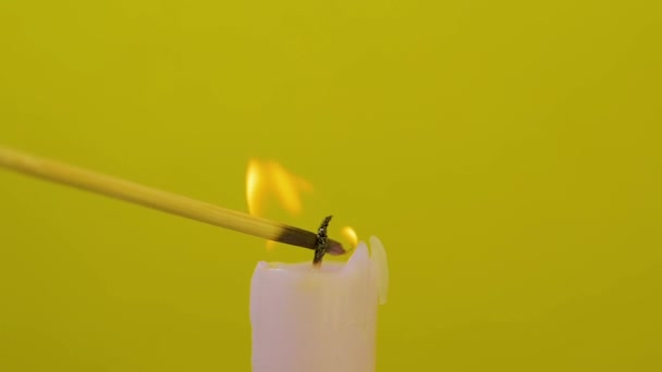 Nahaufnahme eines Kerzendochtes, der mit Splittern auf gelbem Hintergrund angezündet wird und dann ausgeblasen wird — Stockvideo