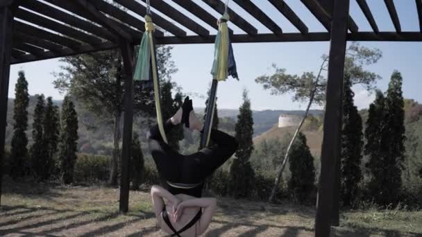 Jonge vrouw beoefent luchtverlegging anti-zwaartekracht yoga in de natuur op zomerdag. Gezond levensstijl en harmonie leven concept. Vrijheid, adem en kalmte. Langzame beweging — Stockvideo