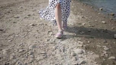 Kumlu sahilde uzun elbiseli bir kadının bacaklarının yakın çekimi.