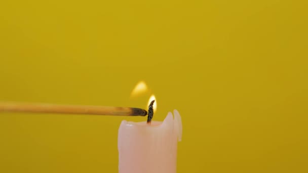 Close-up of candle wick ignited with splinter isolated on yellow background — Stock Video