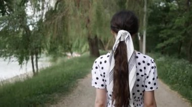 Park 'ta gölde uzun saçlı genç bir kadının portresi. Arkadan görünüm