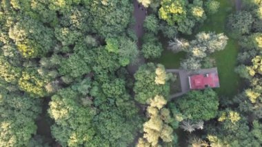 Yaz parkının tepesinden aşağı uçan uçan balkon insanların günbatımında yürüdükleri ormanla