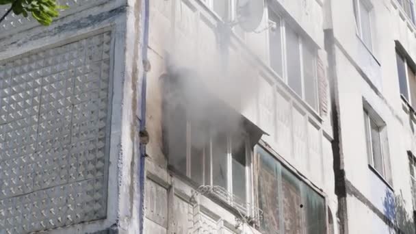 Brandweerlieden slaan het raam van een flatgebouw uit waar rook vandaan komt. Zijaanzicht. Vuur. Rusland, Stavropol, 1.05.20 — Stockvideo