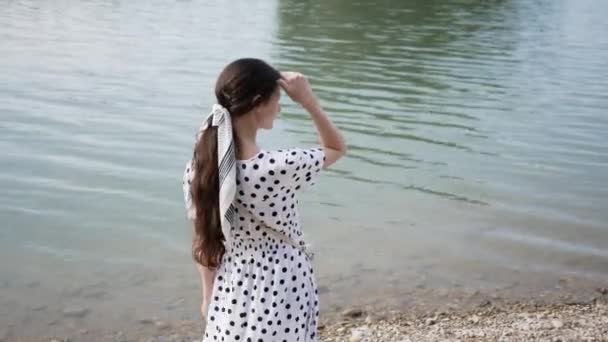 Young woman came to shore of lake and searches for someone looking into distance horizon — Stock Video