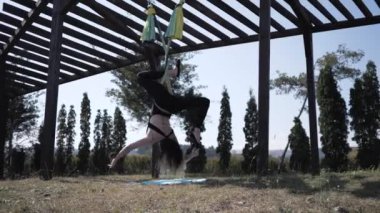 Genç atletik kadın diz kancası ters çevirme serisi yapıyor. Aero yogası. fitness