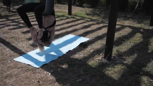 Молодая спортсменка делает упражнения Aero йога поза, asana мост на гамаке в парке на открытом воздухе — стоковое видео