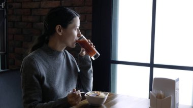 Bir kafede yemek yiyen genç ve güzel bir kadın, sağlıklı yemek, salata ve meyve suyu.