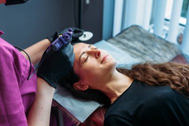 Kaşlar için kalıcı makyaj. Güzellik salonunda kalın kaşlı güzel bir kadının yakın çekimi.