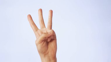 Yakından erkek eli beyaz bir arka planda üç parmak yukarıda..