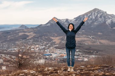 Arka plandaki dağlarda yürüyen, kollarını havaya kaldırmış.