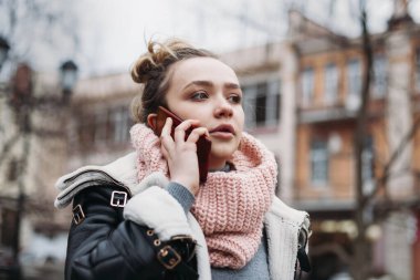 Güz mevsiminde sokakta cep telefonuyla konuşan güzel genç bir kadın..