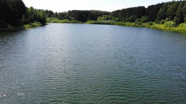 Aerial fly at high speed over water surface of a calm lake in summer Sunny day.