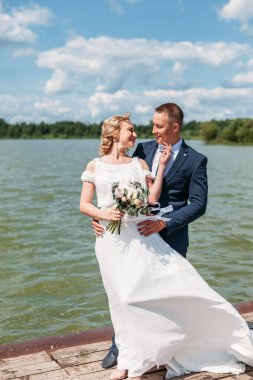 Damat gelini arkadan nazikçe kucaklarken onlar da gölde rüzgarın tadını çıkarıyorlar..