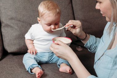 Genç anne oğlunu bir kaşık meyve püresiyle besler..
