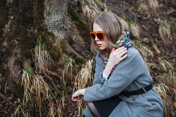 fashion photography. model in silk scarf and sunglasses, dressed in style of 1960s in autumn forest.