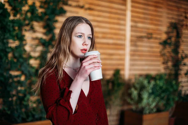 portrait young woman with paper white Cup drinking coffee in cafe.