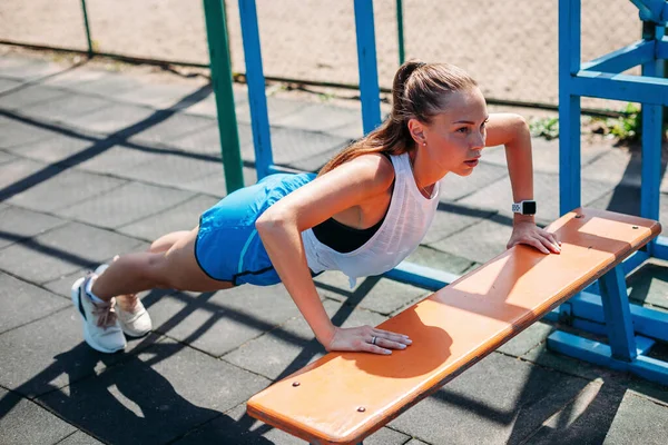 运动年轻性感的女人做推杆 Ups 从板凳上的运动场在运动场上 概念健康的生活方式 — 图库照片