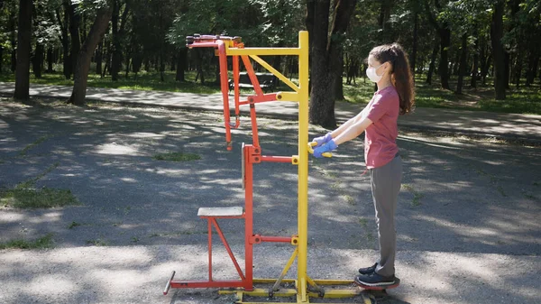 保護面マスクと手袋の若い女性は 公園の屋外運動機器でスポーツのために行く 社会的距離の概念 — ストック写真