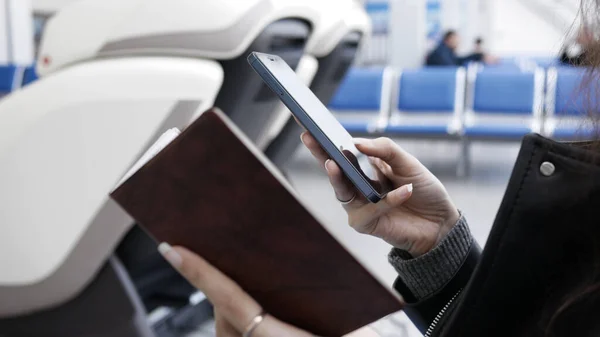 young woman at airport buying  plane ticket through phone, she enters passport data to buy ticket.