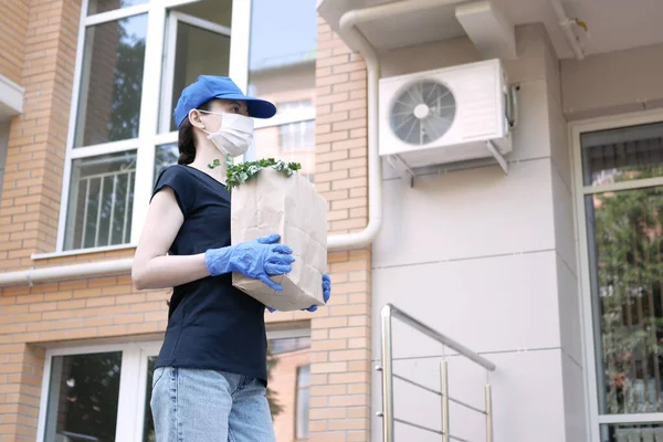 Kurye, koruyucu maskeli kurye ve tıbbi eldivenli teslimatçı paket yemek getiriyor. Karantina altında teslimat hizmeti, hastalık salgını, koronavirüs covid-19 salgını. Evde kal..