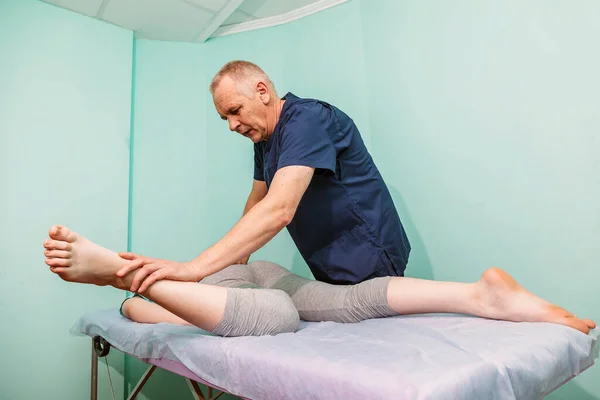 Wanita Berbaring Sofa Dan Seorang Chiropractor Bekerja Dengan Kakinya Fisioterapis — Stok Foto