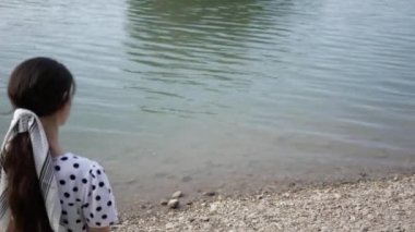 Genç bir kadın gölün kıyısına gider ve uzaktaki birini arar.