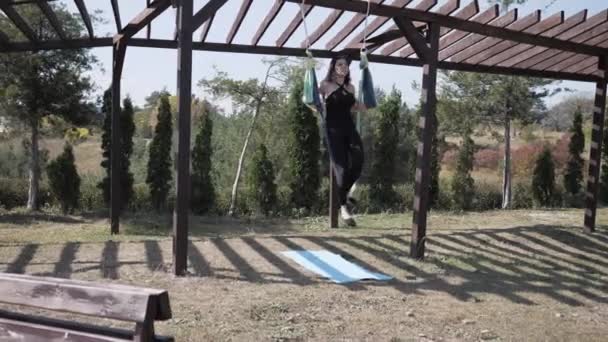 Giovane atleta femminile esegue esercizi di aero yoga su amaca all'aperto nel parco — Video Stock