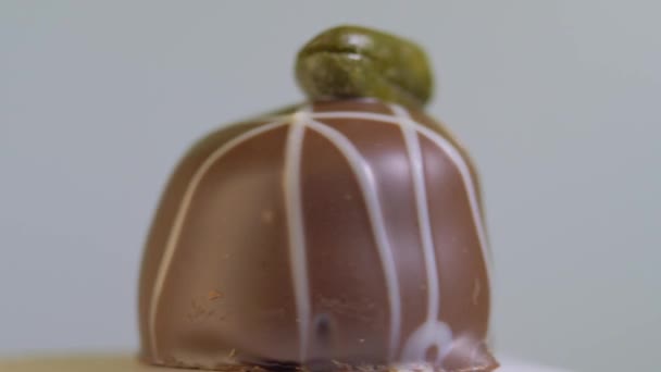Chokladgodis med pistaschmandlar, roterande på vit bakgrund, makro. Söt dessert — Stockvideo