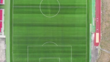 Yeşil çimenli bir futbol sahasının havadan aşağı 4K görüntüsü. Bir spor sahasının üzerinde uçmak