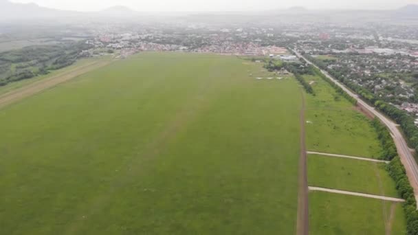 4k Vista aérea superior de un aeródromo de campo con aviones de pie, a lo largo de carretera o ciudad — Vídeo de stock