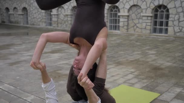 Professionelles akrobatisches Yoga. Fit Kaukasisches Paar übt Kopfstand und balanciert gemeinsam auf Matte im Freien — Stockvideo
