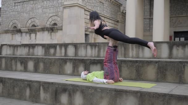 Man and woman practicing acro yoga with partner flying pose in the city outdoors. Doing pair acrobatic workout balancing exercises for beginners, easy acroyoga for healthy couples concept — Αρχείο Βίντεο