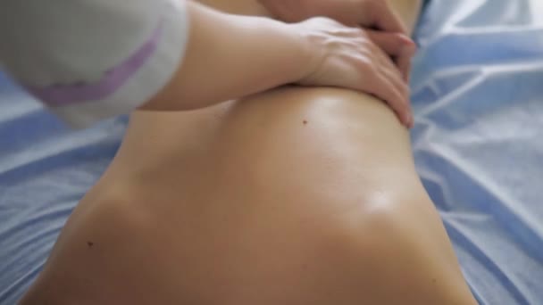 Jovem mulher fazendo massagem no salão de spa. Close-up da mulher relaxante durante a massagem nas costas deitado na mesa de massagem — Vídeo de Stock