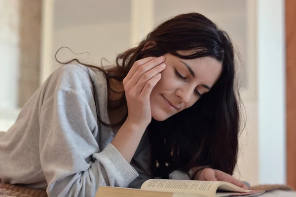 Kvinna läser en bok i sängen — Stockfoto