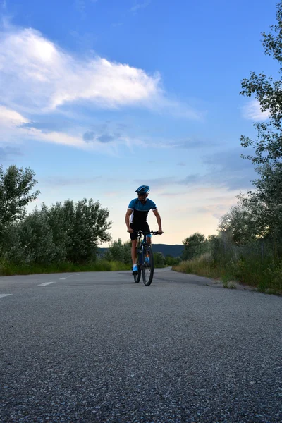 Велосипедист едет на горном велосипеде по одинокой дороге — стоковое фото