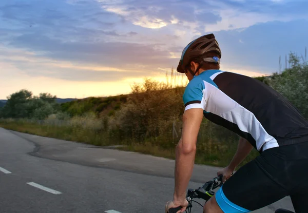 Ciclista indo de bicicleta de montanha ao longo de uma estrada solitária — Fotografia de Stock