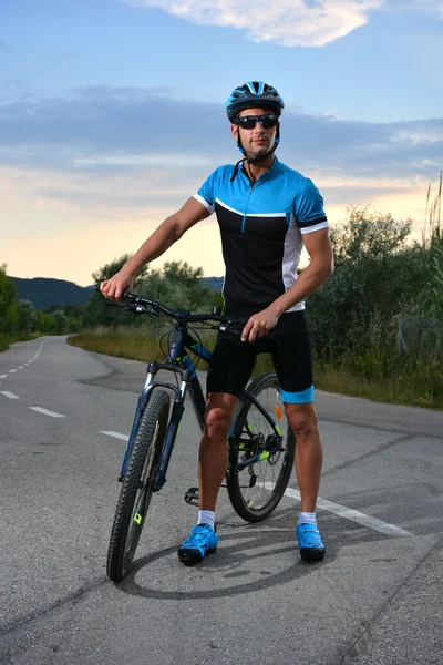 Cyclist going mountain bike along a lonely road — Stock Photo, Image