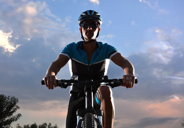 Ciclista indo de bicicleta de montanha ao longo de uma estrada solitária — Fotografia de Stock