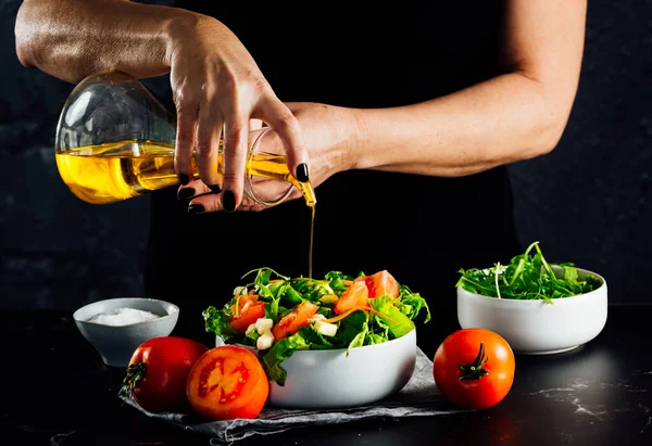 トマト レタス オリーブオイル 塩とサラダを準備する女性健康的な食事の概念 ストックフォト