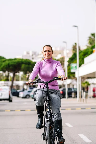 40-year-old woman riding her electric bicycle through the streets of the city (Concept of electric mobility)