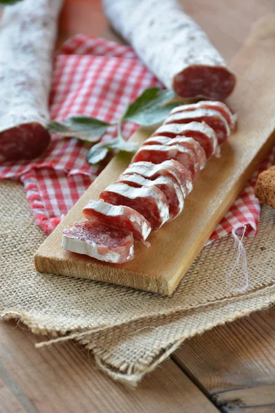 Salame fuet espanhol em uma tábua de corte — Fotografia de Stock