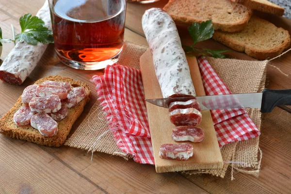 Salami de fuet español en una tabla de cortar —  Fotos de Stock