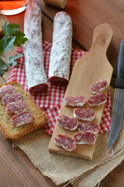 Salame fuet espanhol em uma tábua de corte — Fotografia de Stock