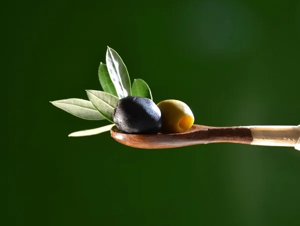 Olio d'oliva che cade su due olive con foglie di ulivo — Foto Stock