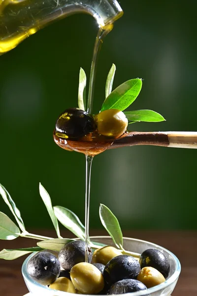 Azeite que cai em duas azeitonas com folhas de oliveira — Fotografia de Stock