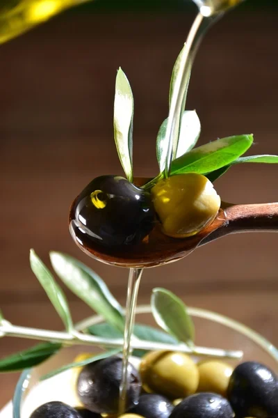 Olive oil falling on two olive with olive leaves — Stock Photo, Image