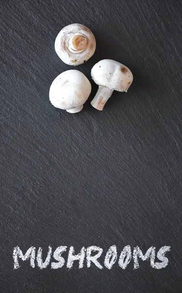 Cogumelos em uma mesa de ardósia preta — Fotografia de Stock