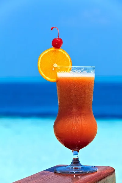 Un vaso de bebida está en una mesa de playa — Foto de Stock