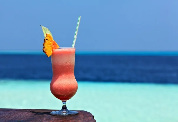 Un vaso de bebida está en una mesa de playa — Foto de Stock